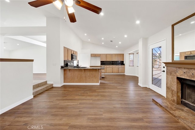 kitchen featuring kitchen peninsula, a tiled fireplace, dark hardwood / wood-style flooring, high vaulted ceiling, and sink