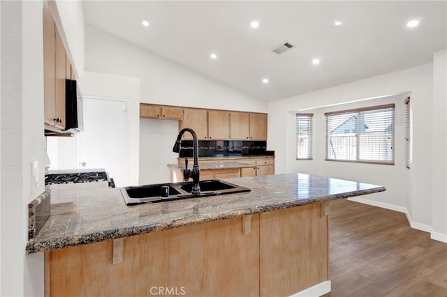 kitchen with lofted ceiling, kitchen peninsula, decorative backsplash, sink, and light hardwood / wood-style flooring