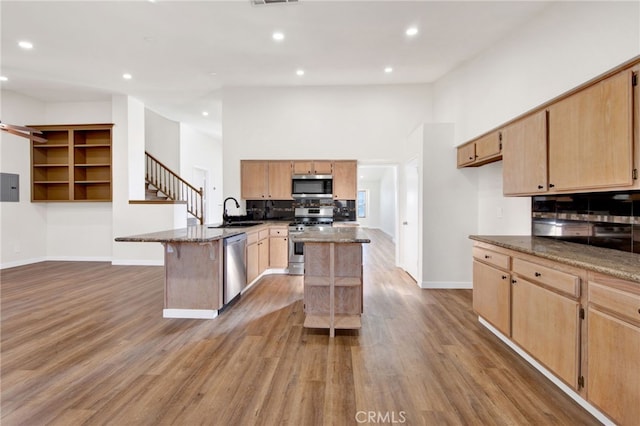 kitchen with appliances with stainless steel finishes, dark stone countertops, and a center island