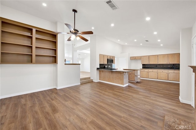 kitchen featuring a kitchen bar, light brown cabinets, dark hardwood / wood-style flooring, kitchen peninsula, and ceiling fan