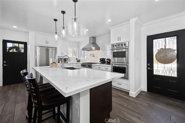 kitchen with extractor fan, appliances with stainless steel finishes, sink, and white cabinets