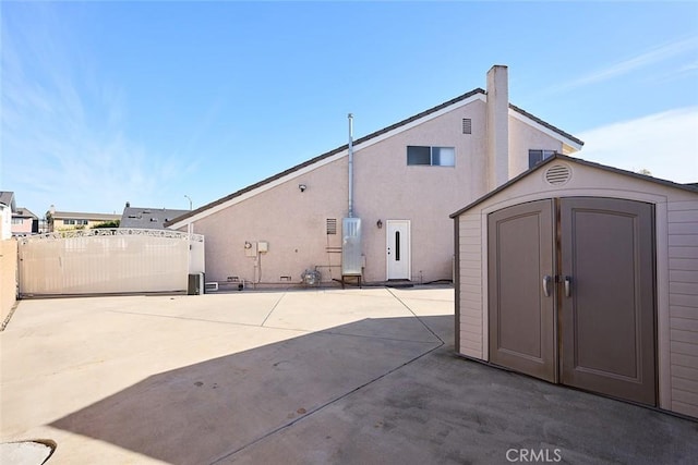 rear view of property with a patio area and a storage unit