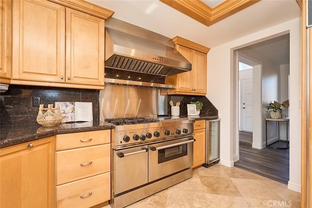 kitchen with tasteful backsplash, double oven range, wall chimney exhaust hood, and dark stone countertops