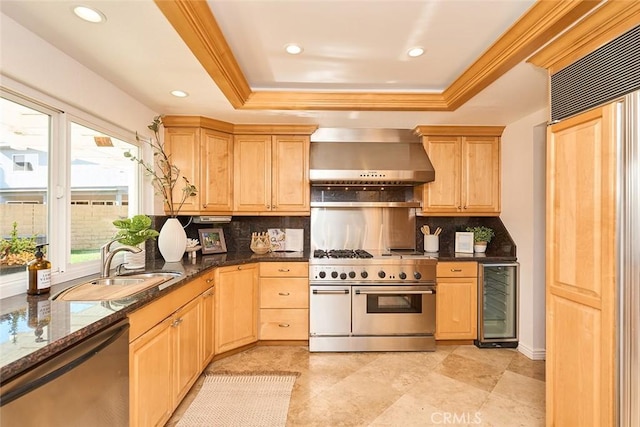 kitchen featuring tasteful backsplash, a tray ceiling, wall chimney range hood, beverage cooler, and stainless steel appliances