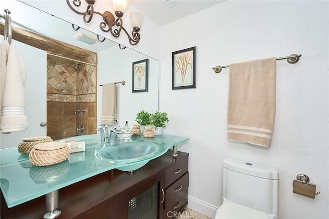 bathroom with vanity, toilet, and a tile shower