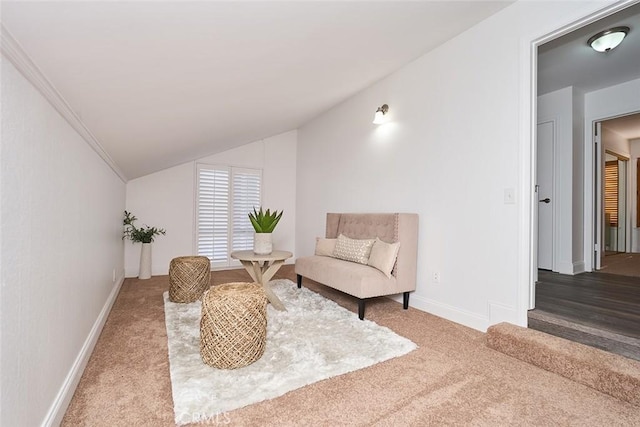 living area with carpet flooring, vaulted ceiling, and ornamental molding