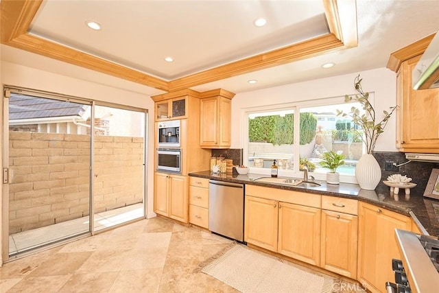 kitchen with appliances with stainless steel finishes, dark stone countertops, decorative backsplash, sink, and a raised ceiling