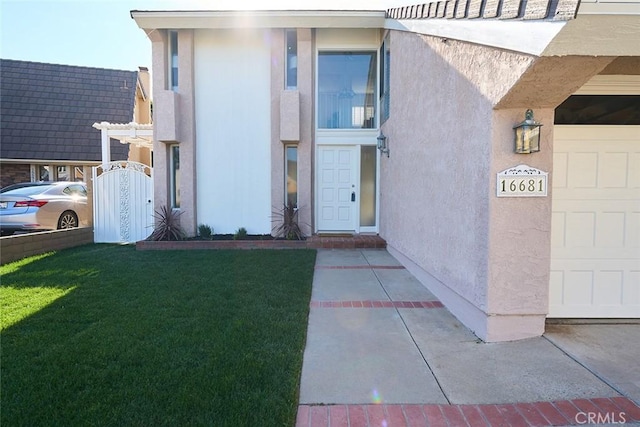 view of exterior entry featuring a garage and a lawn