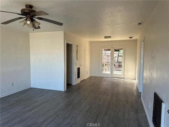 empty room with ceiling fan, dark wood-type flooring, and heating unit