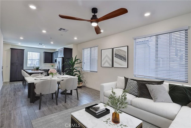 living room featuring dark wood-type flooring and ceiling fan