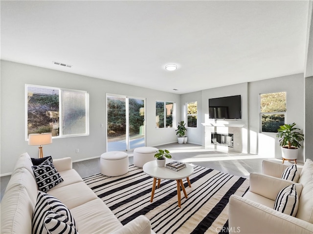 living room with baseboards, visible vents, and a glass covered fireplace