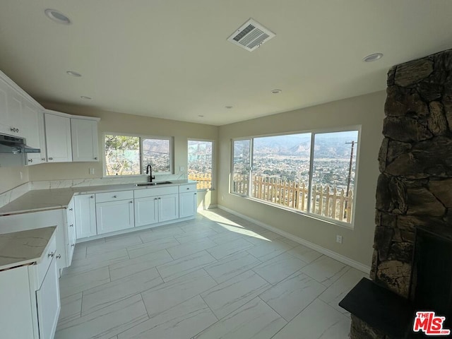 kitchen with light stone countertops, sink, and white cabinetry