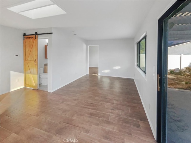 empty room featuring a skylight and a barn door