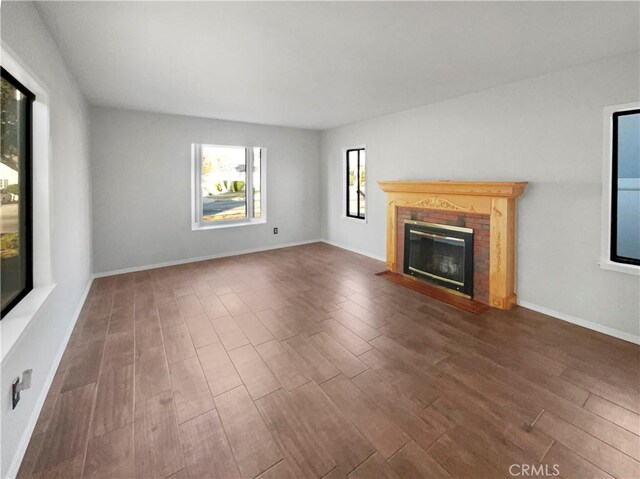 unfurnished living room with a brick fireplace and dark wood-type flooring