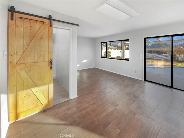 unfurnished room featuring wood-type flooring and a barn door