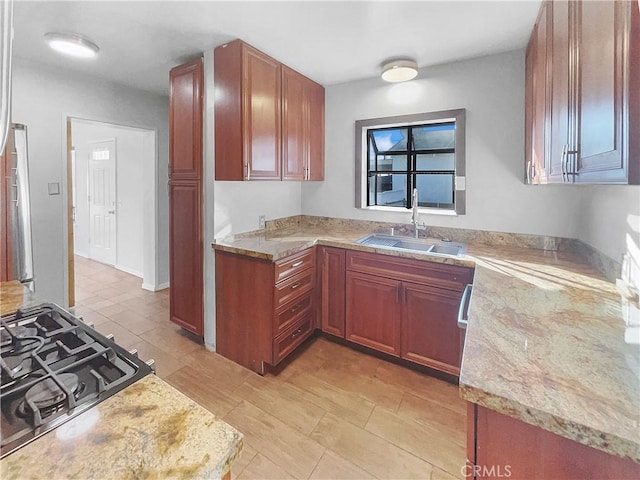 kitchen featuring stovetop, light stone countertops, and sink