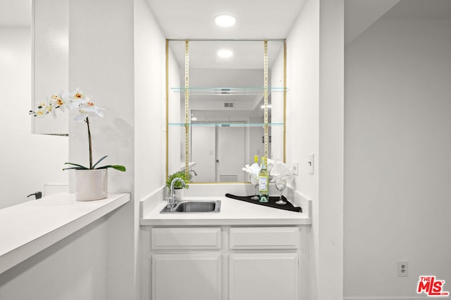 bar with sink and white cabinetry