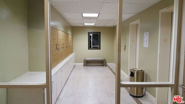 hallway with a mail area and a paneled ceiling