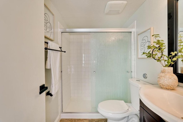 bathroom featuring toilet, vanity, and a shower with shower door