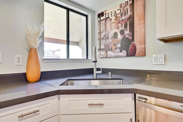 kitchen featuring dishwasher, sink, and white cabinets