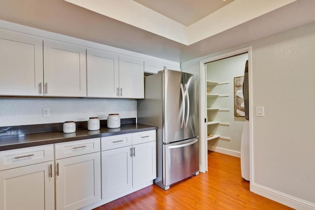 kitchen with stainless steel fridge, light hardwood / wood-style floors, and white cabinets