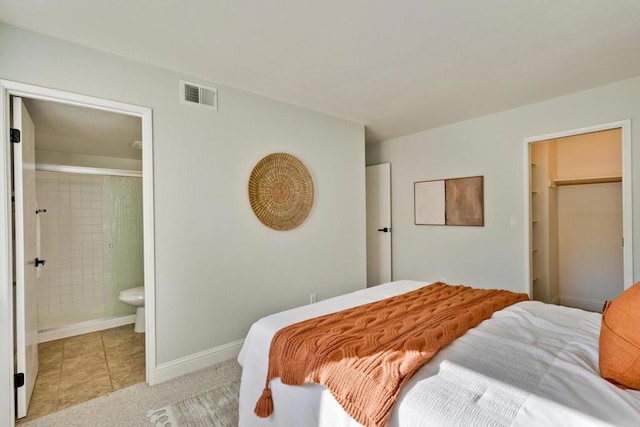 carpeted bedroom with ensuite bath and a walk in closet