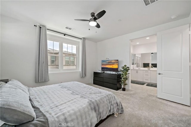 carpeted bedroom with ensuite bathroom and ceiling fan