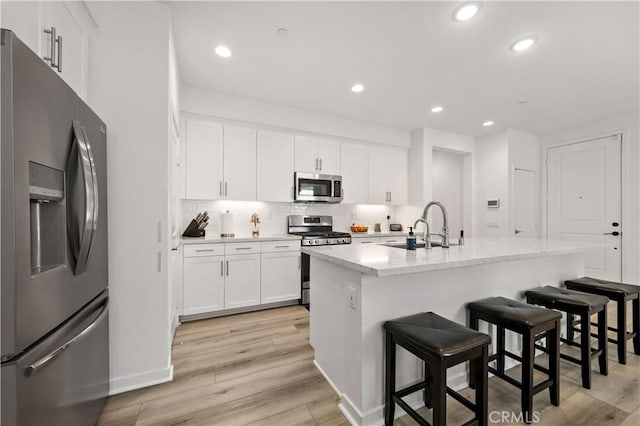 kitchen featuring an island with sink, appliances with stainless steel finishes, sink, and white cabinets