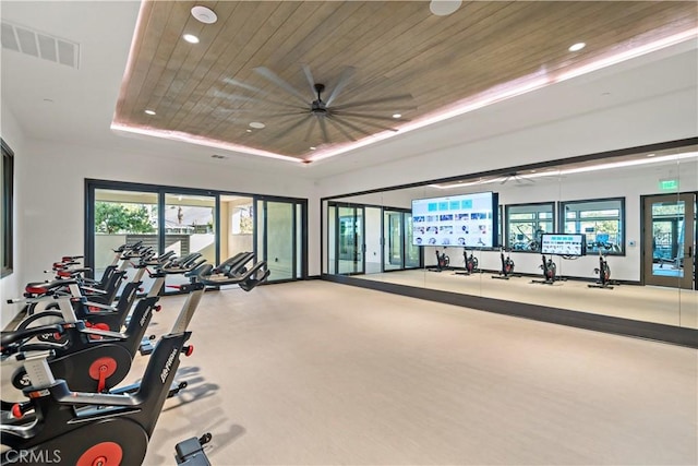 exercise room featuring wood ceiling and a tray ceiling