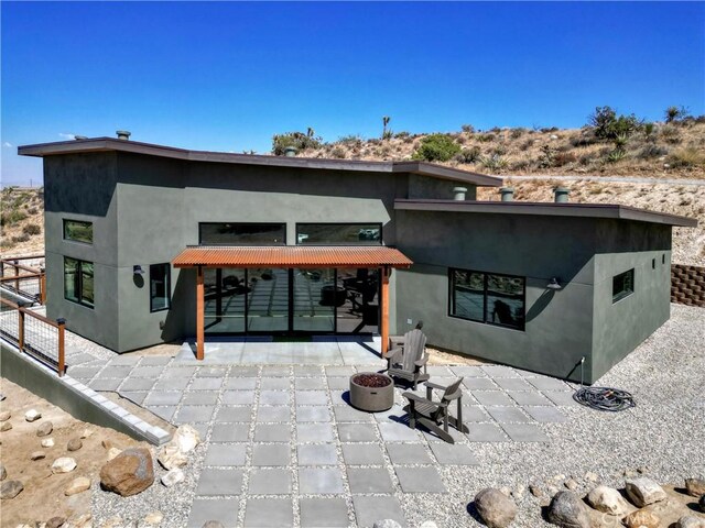 back of property with an outdoor fire pit, a patio area, and stucco siding