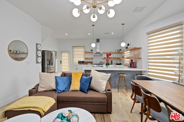 living room with sink, an inviting chandelier, and light wood-type flooring