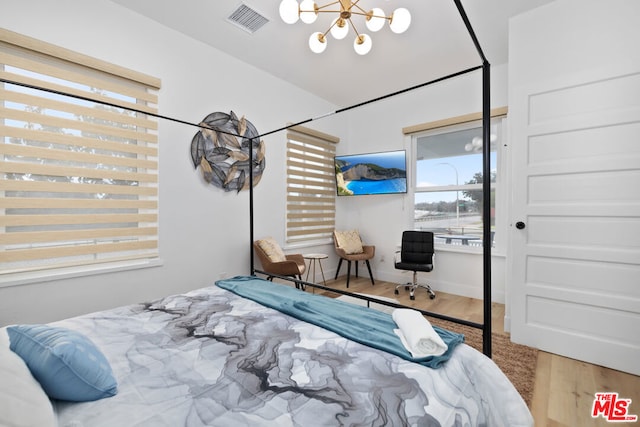 bedroom with hardwood / wood-style floors and an inviting chandelier