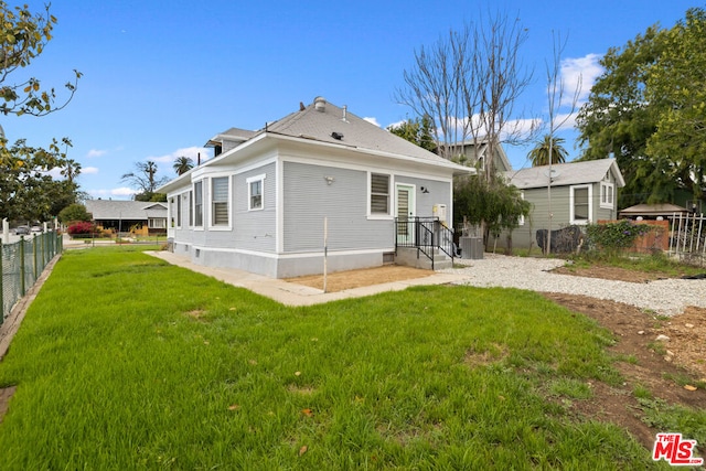 back of house with cooling unit and a yard