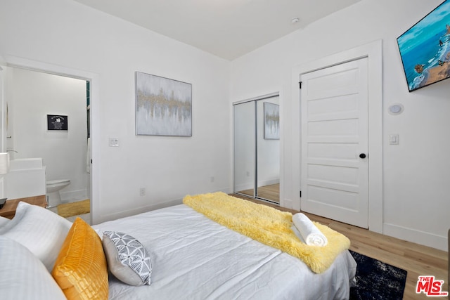 bedroom with a closet, ensuite bathroom, and hardwood / wood-style floors