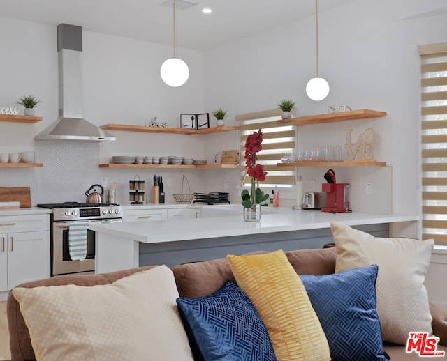 kitchen with backsplash, pendant lighting, stainless steel range with gas stovetop, white cabinetry, and wall chimney exhaust hood