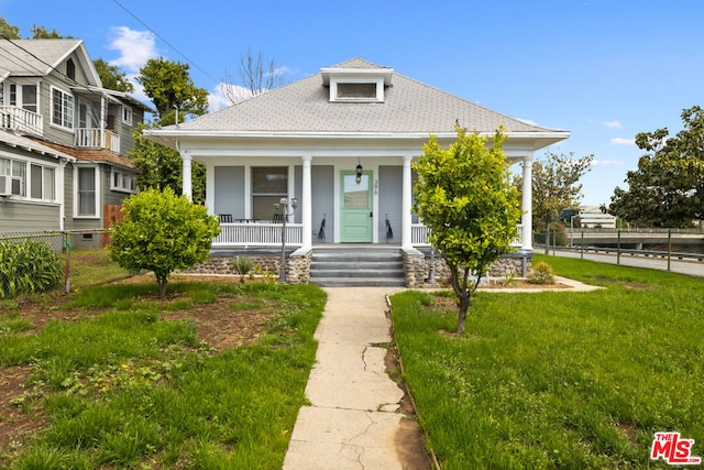 bungalow featuring covered porch and a front lawn