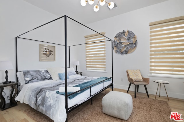 bedroom featuring multiple windows, a notable chandelier, and hardwood / wood-style floors