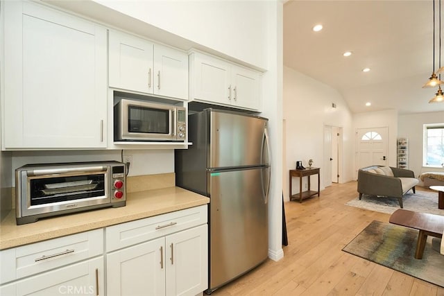 kitchen featuring stainless steel appliances, light hardwood / wood-style floors, white cabinetry, and decorative light fixtures