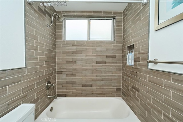 bathroom featuring toilet and tiled shower / bath