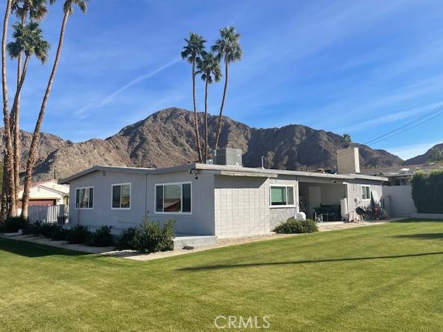 rear view of property with a mountain view and a lawn