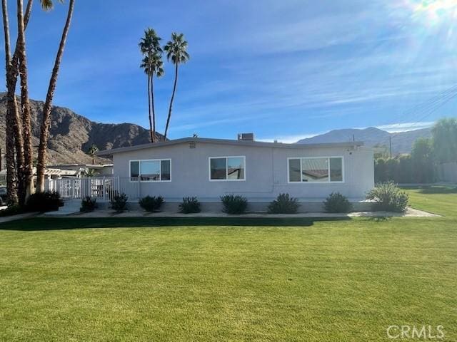 rear view of house with a mountain view and a yard