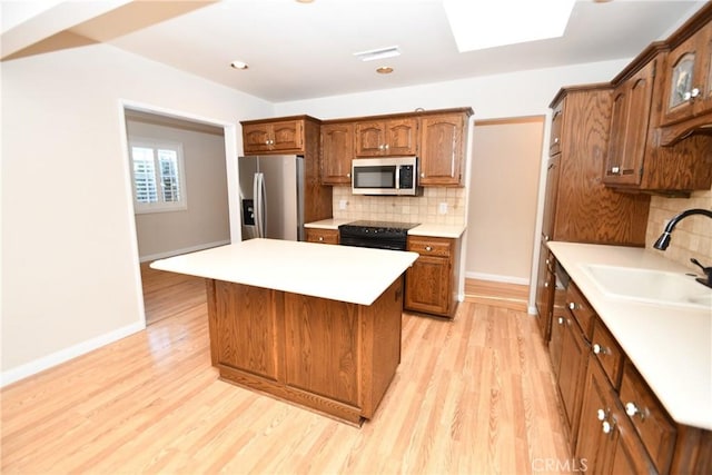 kitchen featuring backsplash, a center island, sink, light wood-type flooring, and appliances with stainless steel finishes