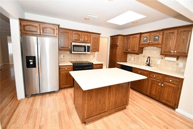 kitchen with a kitchen island, decorative backsplash, sink, light wood-type flooring, and stainless steel appliances