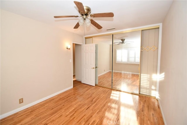 unfurnished bedroom with a closet, light hardwood / wood-style floors, and ceiling fan