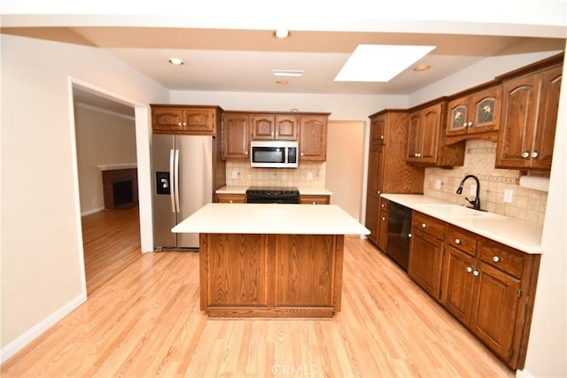 kitchen with black appliances, a kitchen island, tasteful backsplash, light hardwood / wood-style floors, and sink