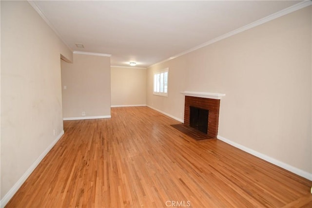 unfurnished living room with light wood-type flooring, a brick fireplace, and crown molding