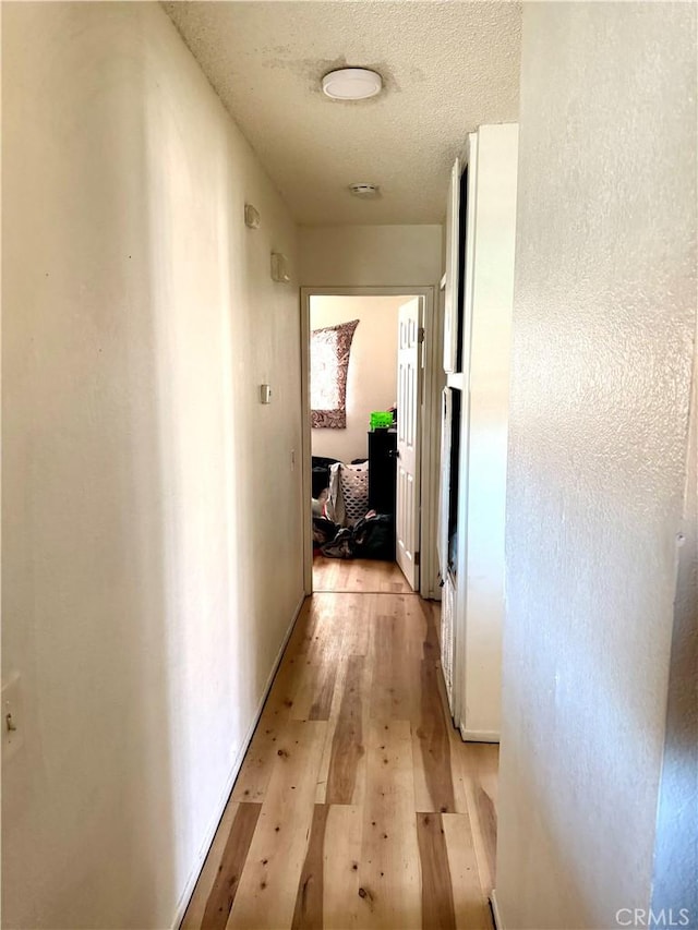 corridor featuring a textured ceiling and light hardwood / wood-style floors