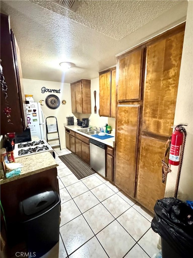 kitchen featuring light tile patterned floors, sink, white appliances, and a textured ceiling