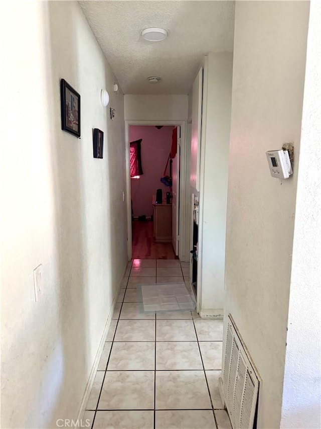 corridor with a textured ceiling and light tile patterned flooring