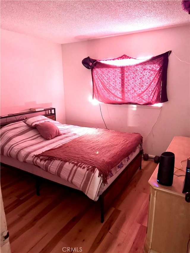 bedroom featuring wood-type flooring and a textured ceiling